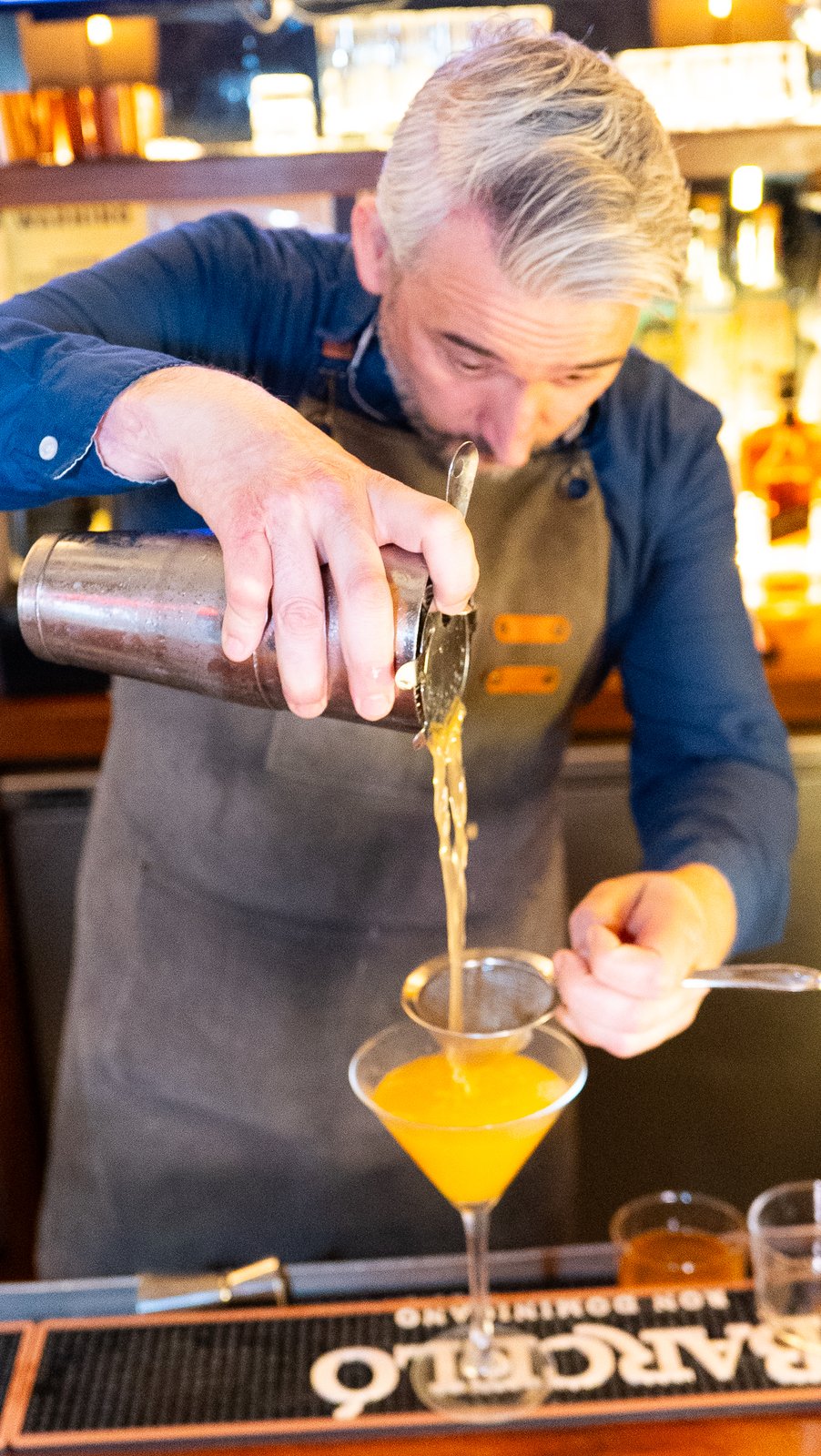 Bartender straining a cocktail into a glass at a NYC restaurant, shot for a Getalife Studios client