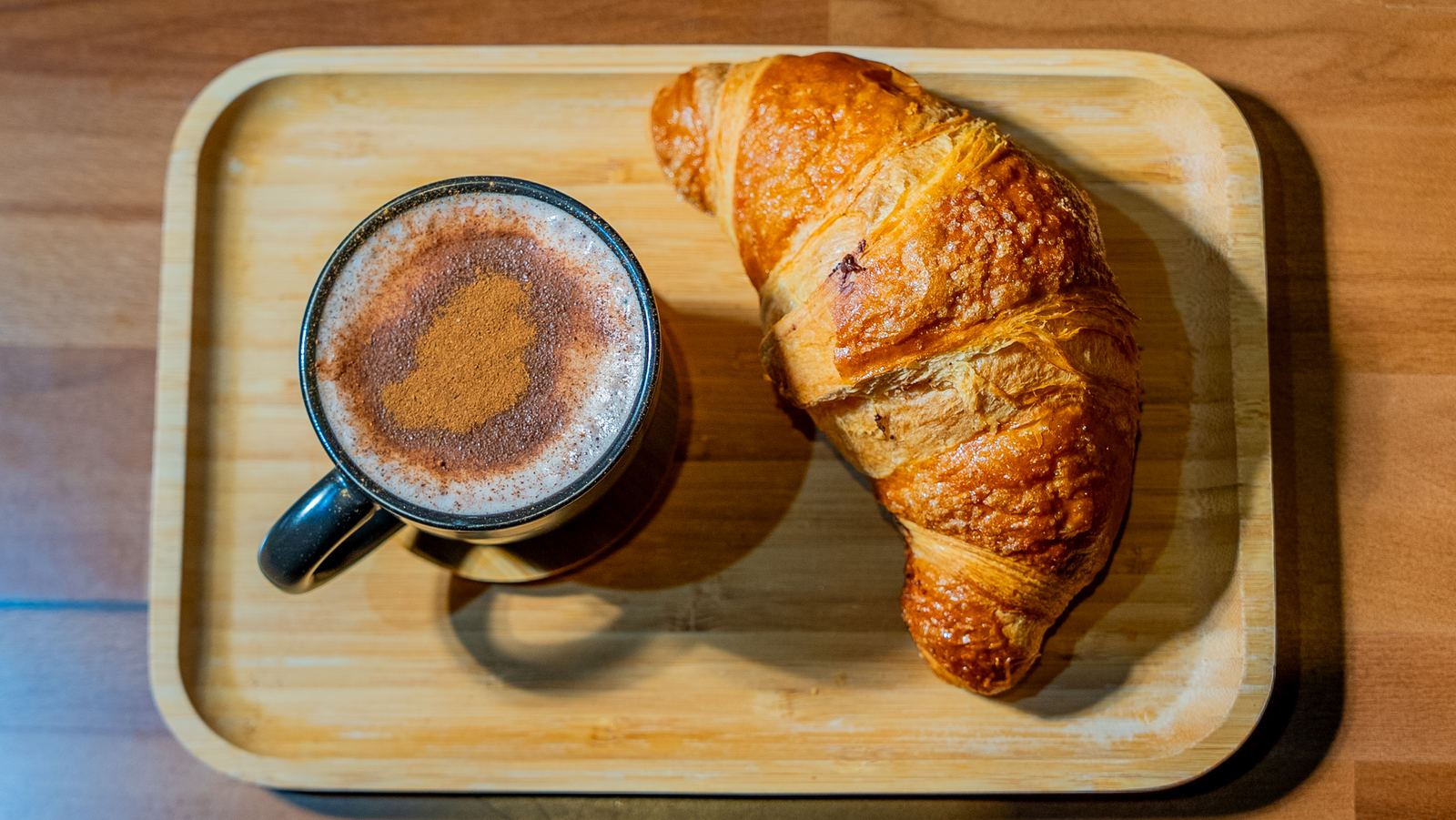 Close-up of a croissant with crumbs on a wooden tray at a NYC café