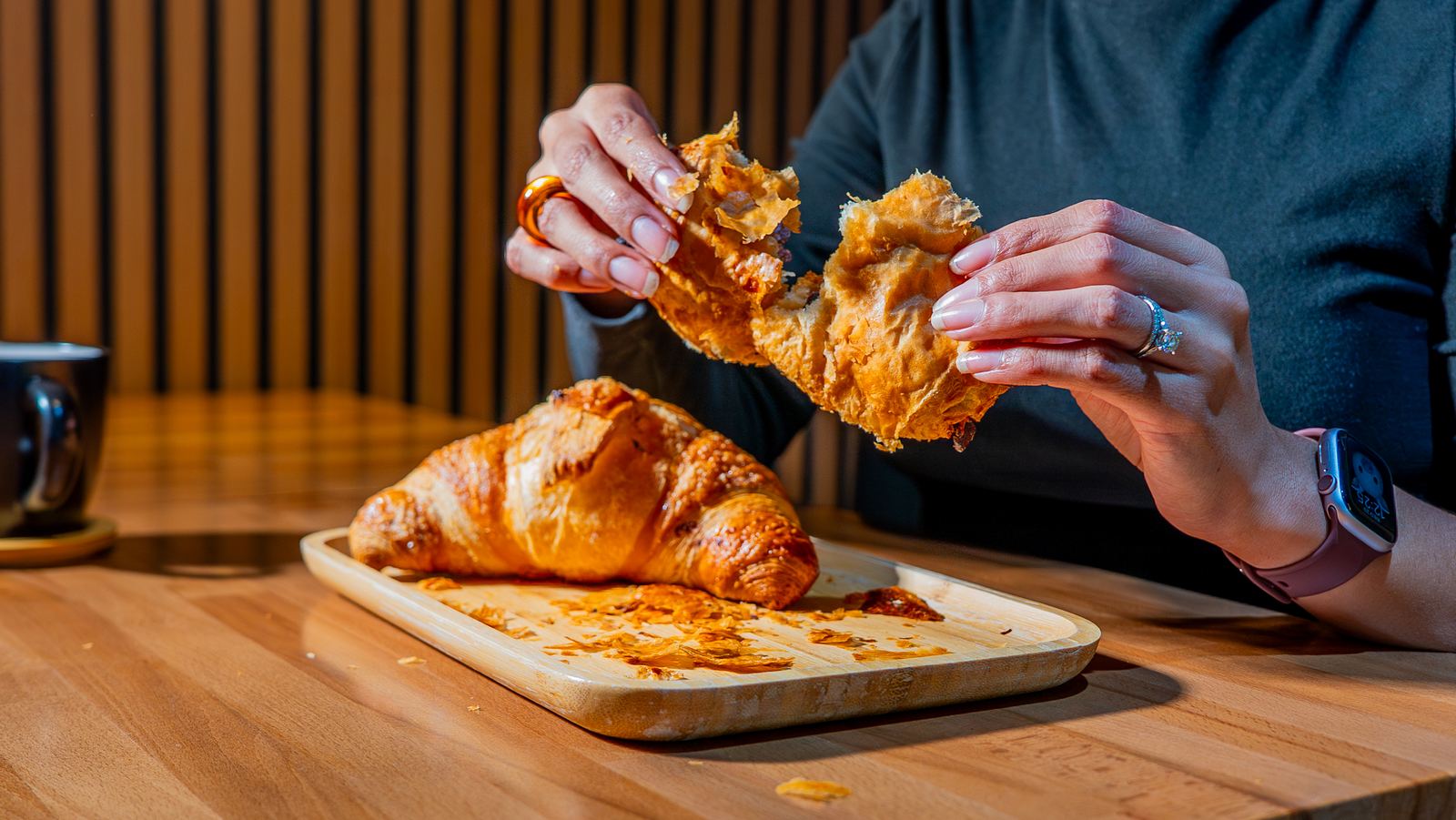 Hands pulling apart a fresh croissant at a NYC café