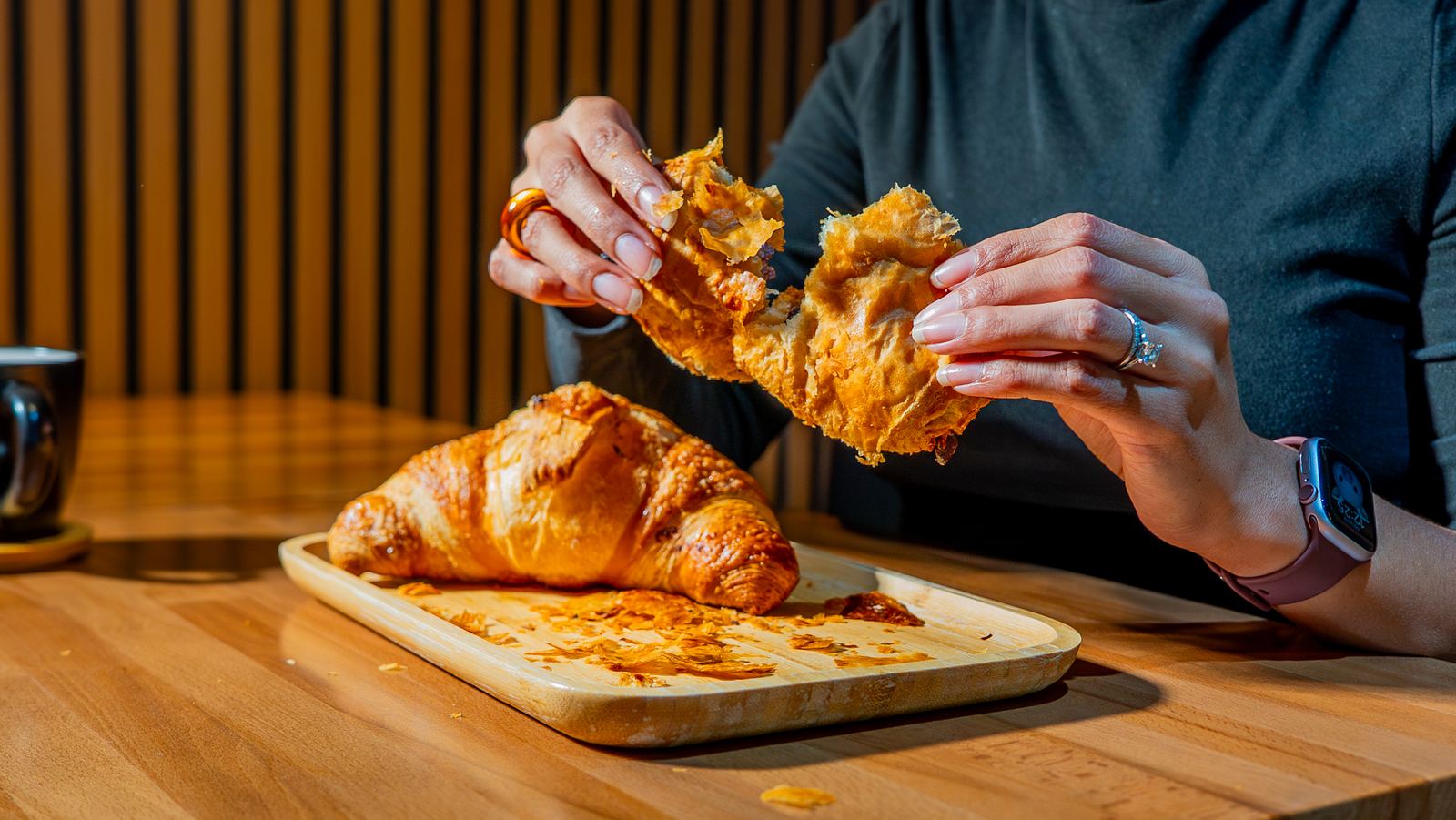 Overhead shot of a mug and croissant on a wooden tray at a NYC café