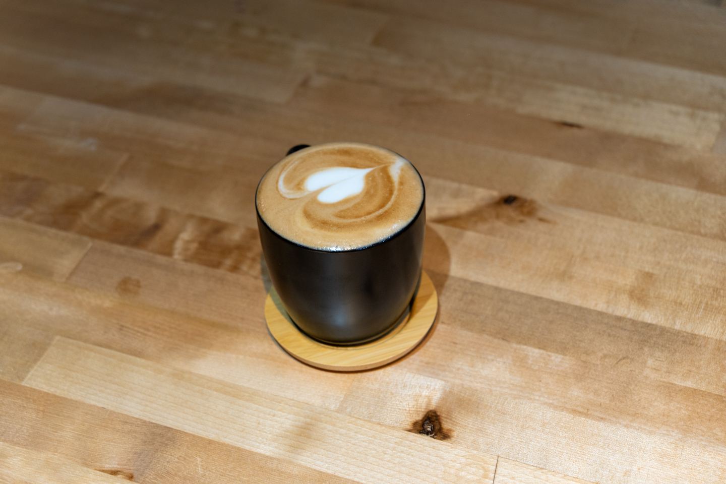 Latte with heart-shaped latte art on a wooden table at a NYC café